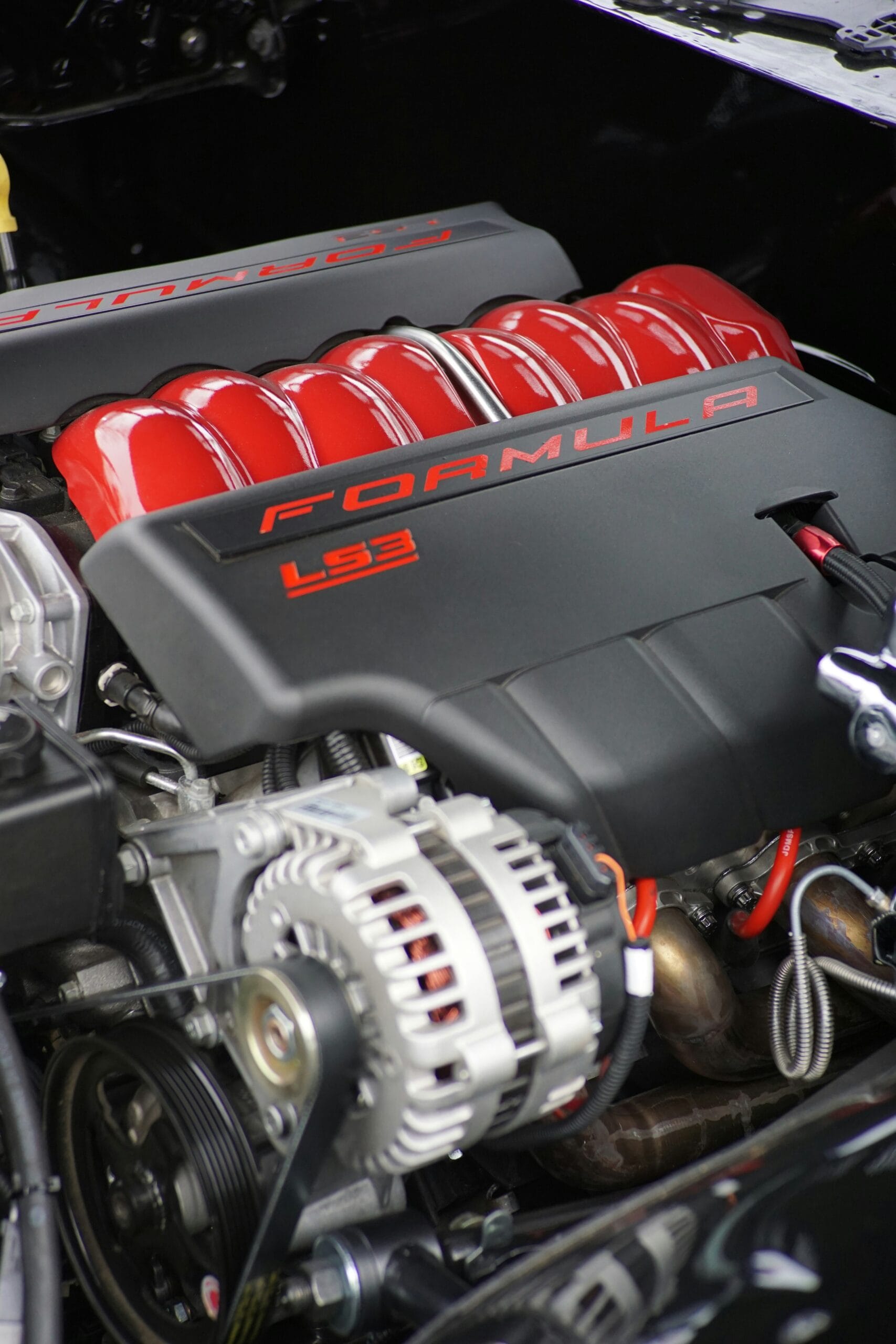 GM LS3 engine with red intake runners and black FORMULA covers, clean engine bay close-up