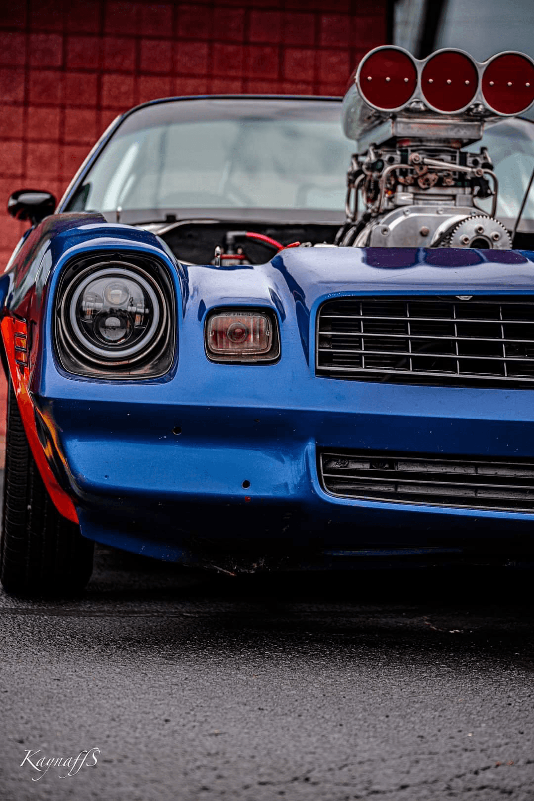 Front close-up of a blue second-gen Camaro with a supercharger and blower hat, custom headlights, and drag racing stance — Pandemic build.