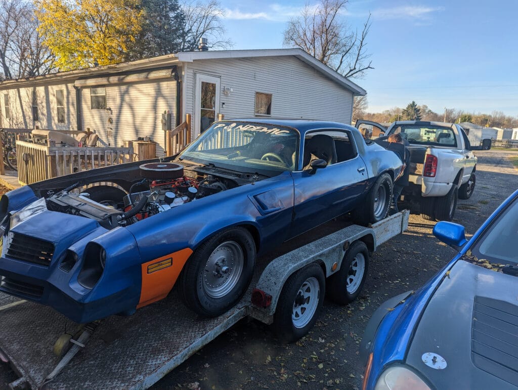 1980 Camaro Z28 Pandemic loaded on a trailer during the early build, showing the small-block engine, fat rear tires, and raw street-car stance.
