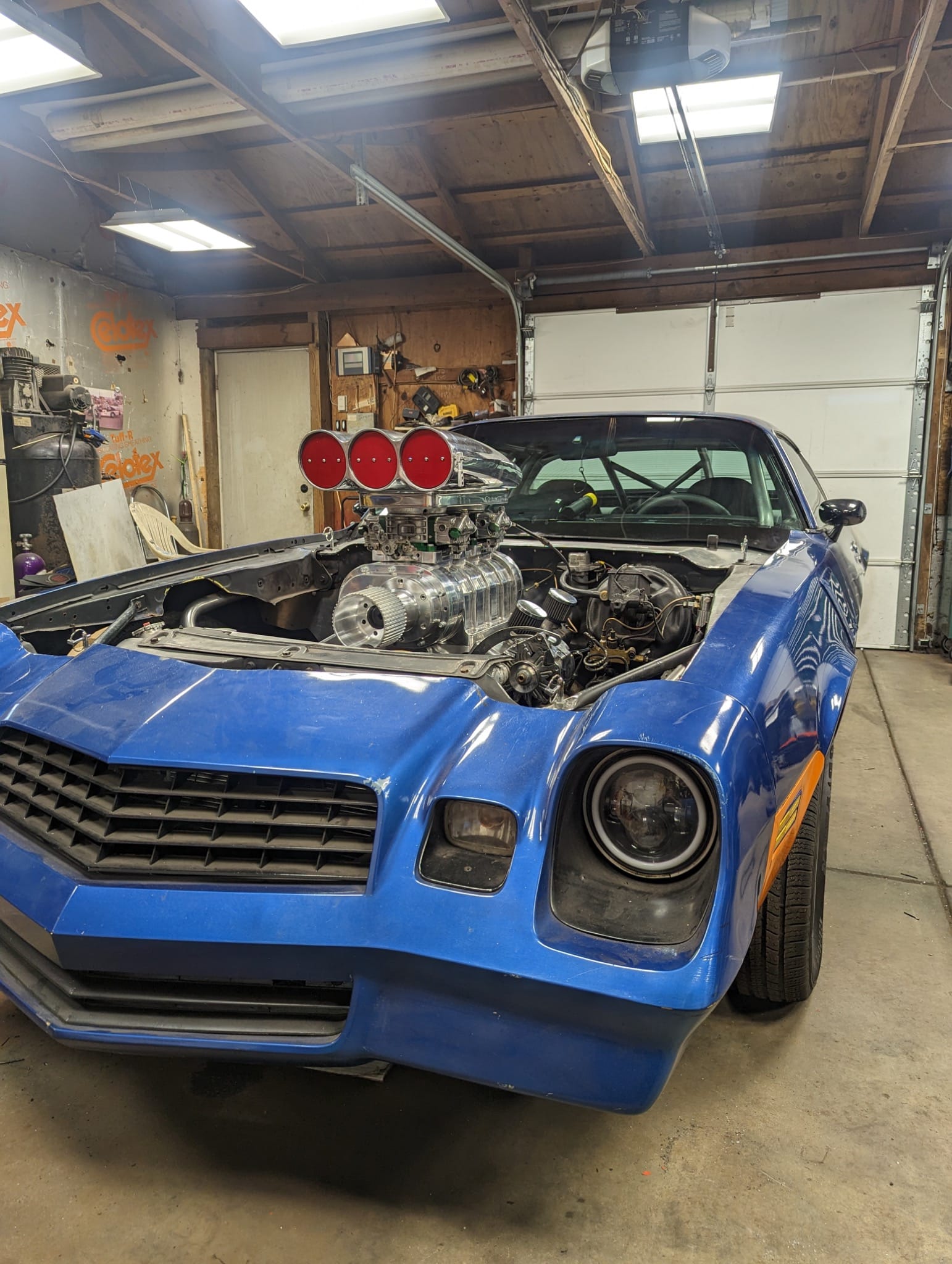 Front view of a blue second-gen Camaro in the garage with the hood removed and a polished blower setup exposed.