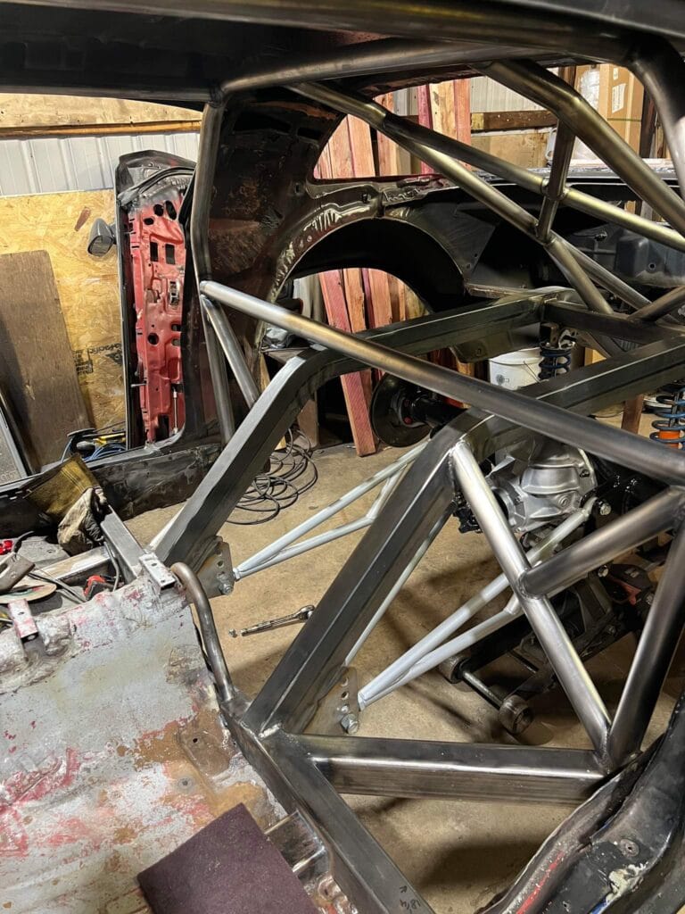 Fabrication view of the Pandemic 1980 Camaro Z28 showing the custom roll cage, back-half frame rails, and TIG-welded chassis structure during construction.