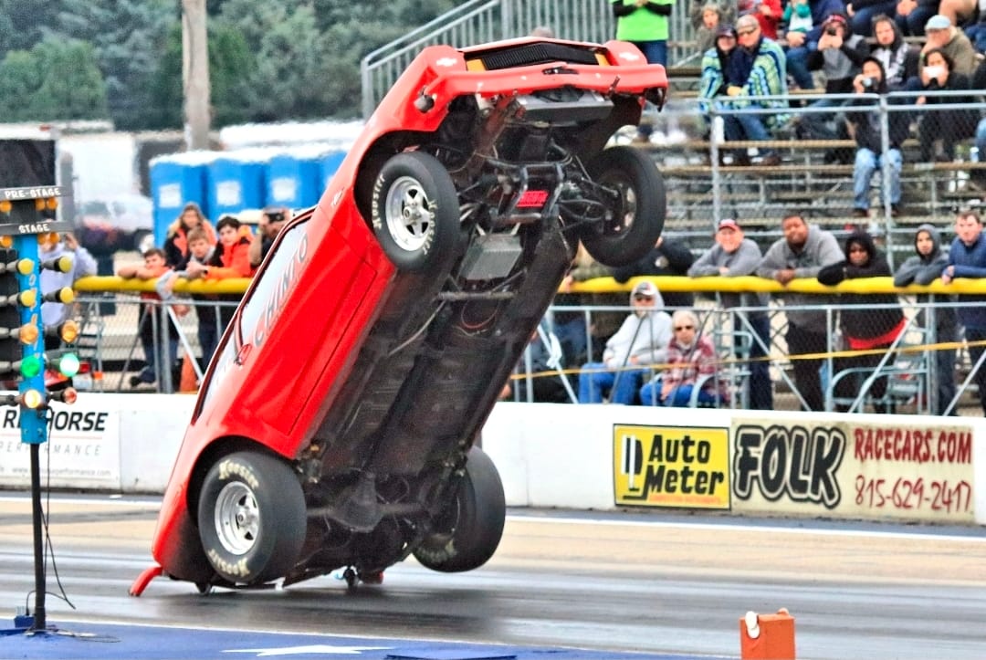 Team Chinto Ford Pinto nearly vertical during an extreme wheelstand, rear bumper contacting the track with front wheels fully airborne