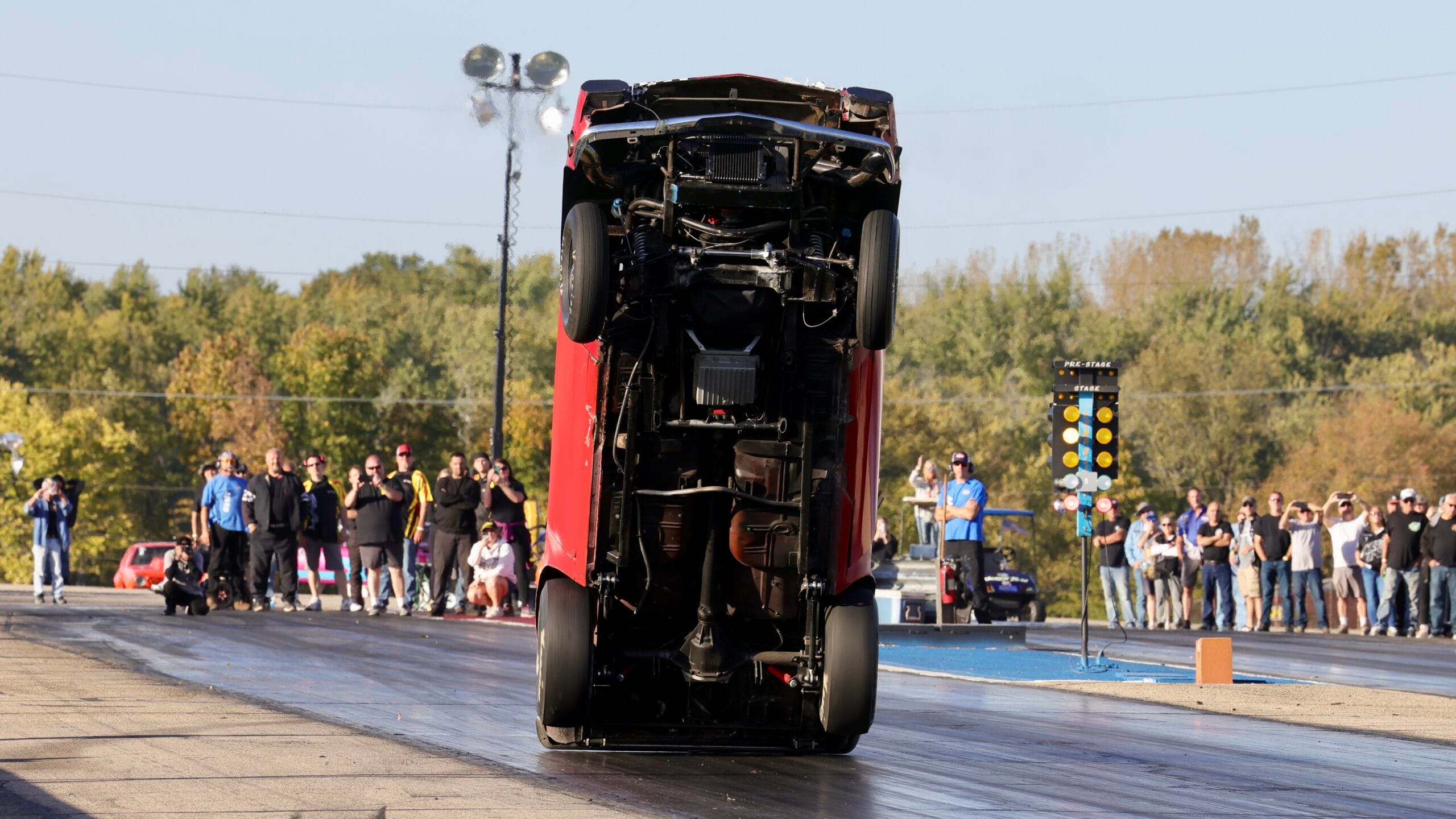 Team Chinto outlaw wheelstanding Pinto completely airborne with all four tires off the ground, car standing nearly vertical during a drag strip pass.